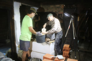 Muurarimestari Hardi Ojaste (oik.) ja ja amerikkalainen Richard Olsen tyhjentävät leivinuunin pohjaa kalkkikiven paloista ja savesta. 